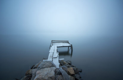 A foggy lake with a wooden dock.