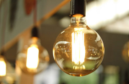 A group of light bulbs hanging from a ceiling, prominently illuminating the CEO and executives in the room.