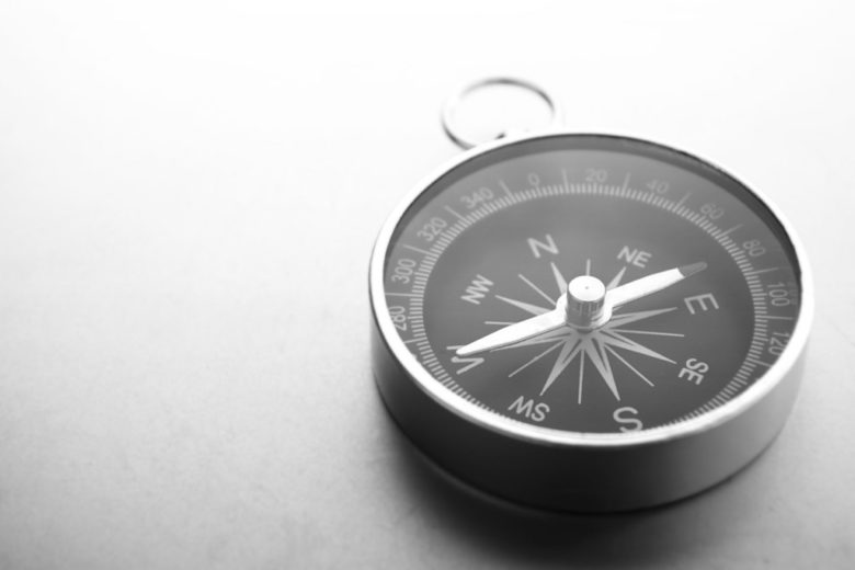 A black and white photo of a CEO holding a compass.
